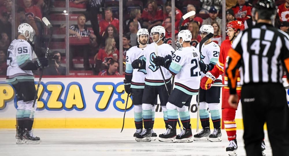 CALGARY, AB - OCTOBER 03: Seattle Kraken Center Matty Beniers (10) celebrates a goal with Seattle Kraken Defenceman Vince Dunn (29) Seattle Kraken Left Wing Andre Burakovsky (95) and teammates during the third period of an NHL pre-season game between the Calgary Flames and the Seattle Kraken on October 3, 2022, at the Scotiabank Saddledome in Calgary, AB. (Photo by Brett Holmes/Icon Sportswire)