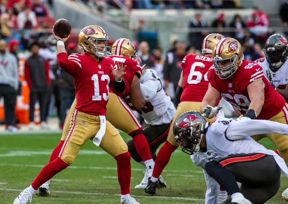 SGPN kicks off Week 14 with the Thursday Night Football Best Bets and Props article. Follow along each night as we roll out our plethora of picks and props from all ranges of odds and potential returns. We start here with Thursday Night Football. The San Francisco 49ers visiting the Seattle Seahawks. These NFC west foes will meet for the second time this season. A lot has changed since the week 2 matchup. Trey Lance was the starter for the 49ers but was lost to an ankle injury in this game. Familiar face Jimmy Garoppolo stepped in and led San Francisco to the 27-7 victory. Thursday Night Football Best Bets and Props The Spread The spread for this matchup is currently -3 in favor of the San Francisco 49ers. <a href=